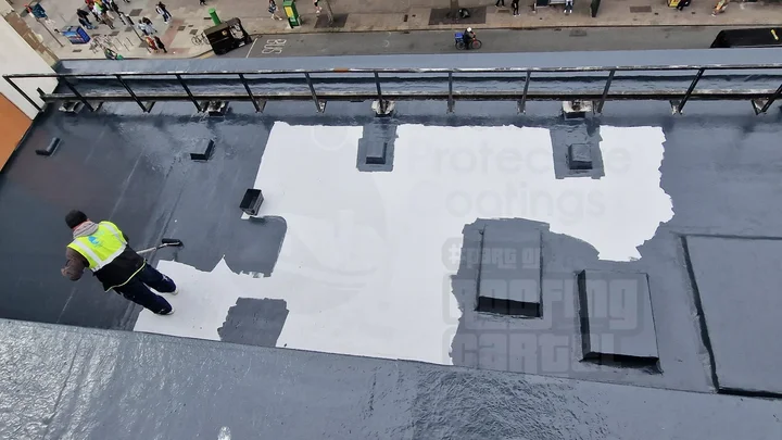 Professional applicator applying LAVA 20 liquid waterproofing topcoat over reinforcement on a flat roof